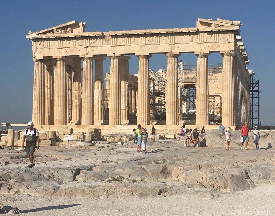 A fairly clear view of ruins with eight columns and intricate carvings connecting them together at the top.