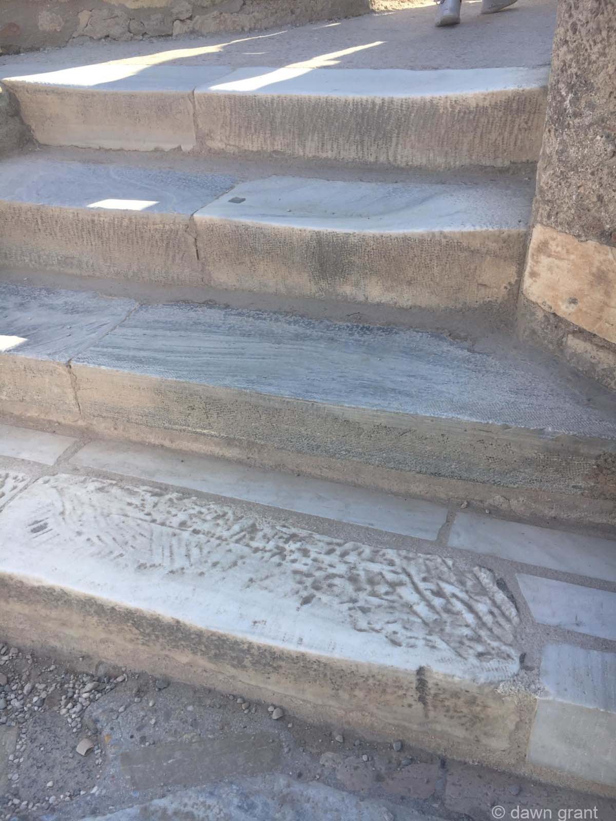 A close look at stone stairs that have been worn down by feet climbing them over centuries.