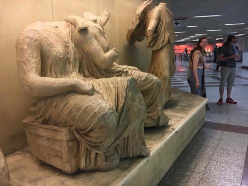 Three obviously ancient statues missing arms and legs in a Metro building corridor.